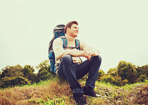 adventure, travel, tourism, hike and people concept - smiling man with backpack sitting on ground