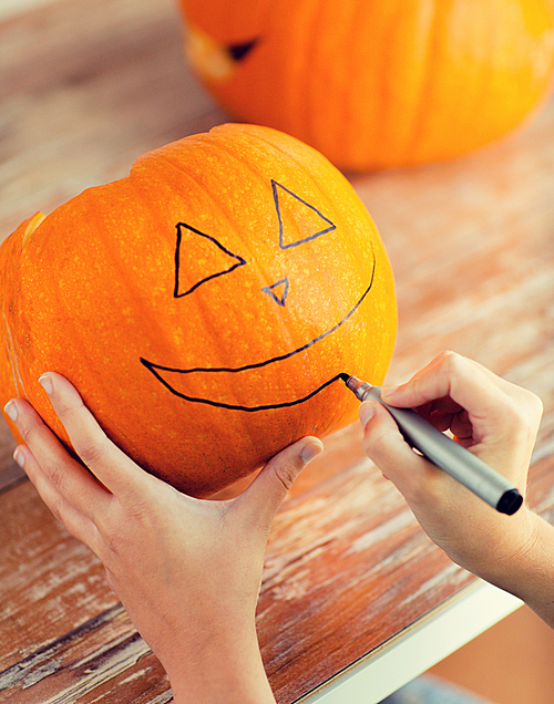 holidays, halloween, decoration and people concept - close up of woman with pumpkins at home