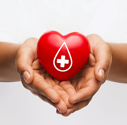 healthcare, medicine and blood donation concept - african american female hands holding red heart with donor sign