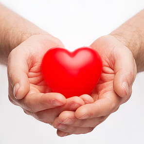 health, medicine and charity concept - close up of male hands with small red heart