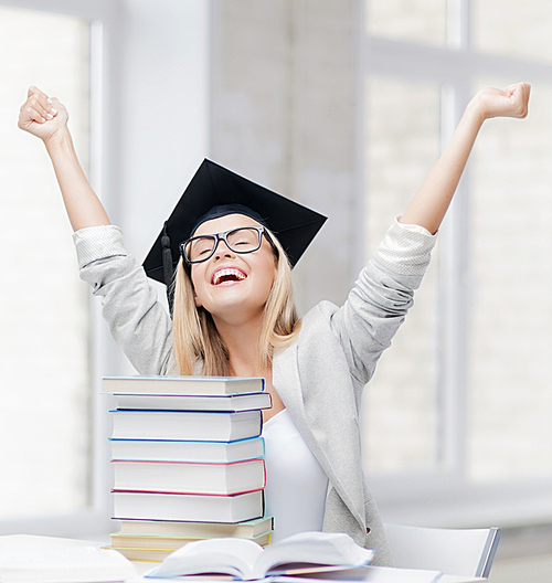 happy student in graduation cap with stack of books