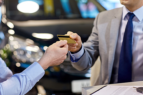 auto business, sale and people concept - close up of customer giving credit card to car dealer in auto show or salon