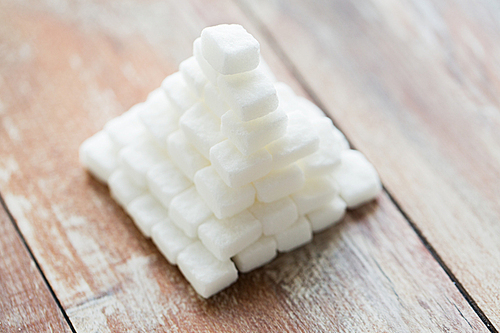 food, junk-food, cooking and unhealthy eating concept - close up of white sugar pyramid on wooden table