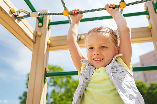 summer, childhood, leisure and people concept - happy little girl on children playground climbing frame