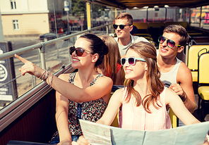 friendship, travel, vacation, summer and people concept - group of smiling friends with map traveling by tour bus