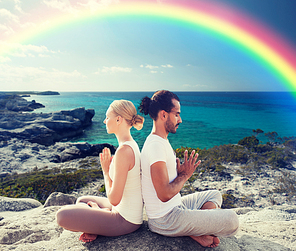 fitness, sport, people, yoga and lifestyle concept - happy couple meditating in lotus pose on summer beach