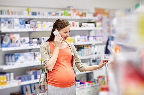 pregnancy, medicine, pharmaceutics, health care and people concept - happy pregnant woman calling on smartphone and choosing medication at pharmacy