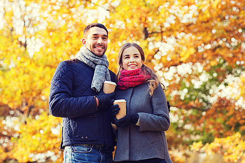 love, relationship, season, friendship and people concept - smiling couple with coffee cups in autumn park