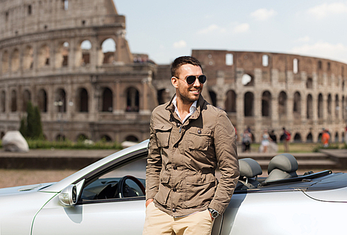 travel, tourism, road trip, transport and people concept - happy man near cabriolet car over coliseum in rome background