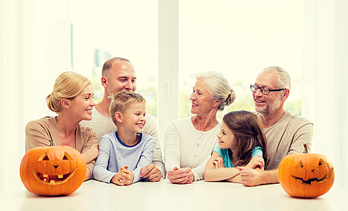 family, happiness, generation, holidays and people concept - happy family making halloween pumpkins at home