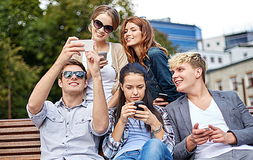 summer, technology, education and teenage concept - group of happy students or teenagers with smarphones taking selfie and texting messages at campus