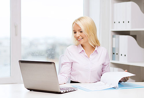 education, business and technology concept - smiling businesswoman or student with laptop computer and documents in office