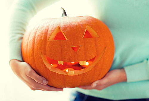 holidays, halloween, decoration and people concept - close up of woman with pumpkins at home