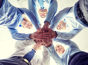 business, people and teamwork concept - smiling group of businesspeople standing in circle and putting hands on top of each other
