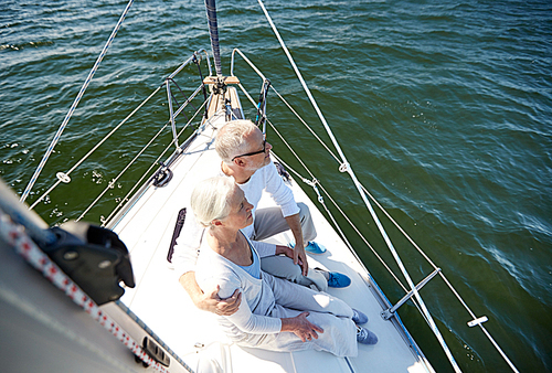 sailing, age, tourism, travel and people concept - happy senior couple hugging on sail boat or yacht deck floating in sea