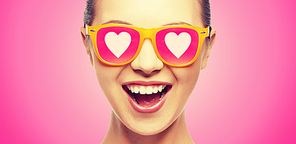 love, happiness and valentines day concept - amazed teen girl in sunglasses with hearts on pink background