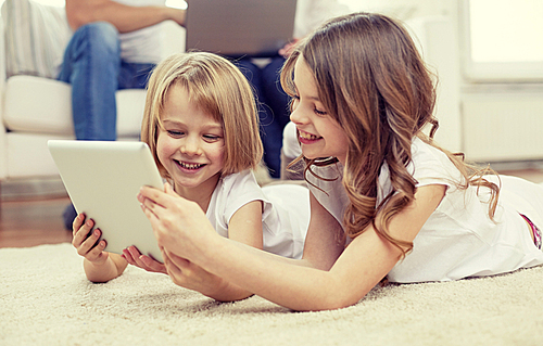 people, family, technology and children concept - happy little girls playing with tablet pc computer at home