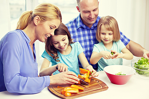 food, children, culinary and people concept - happy family with two kids cooking vegetables at home