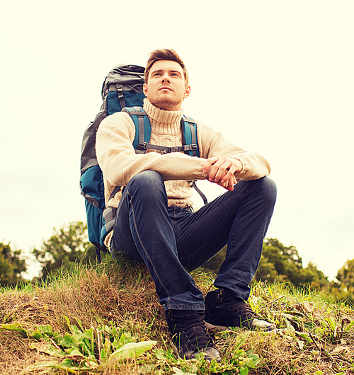 adventure, travel, tourism, hike and people concept - man with backpack sitting on ground