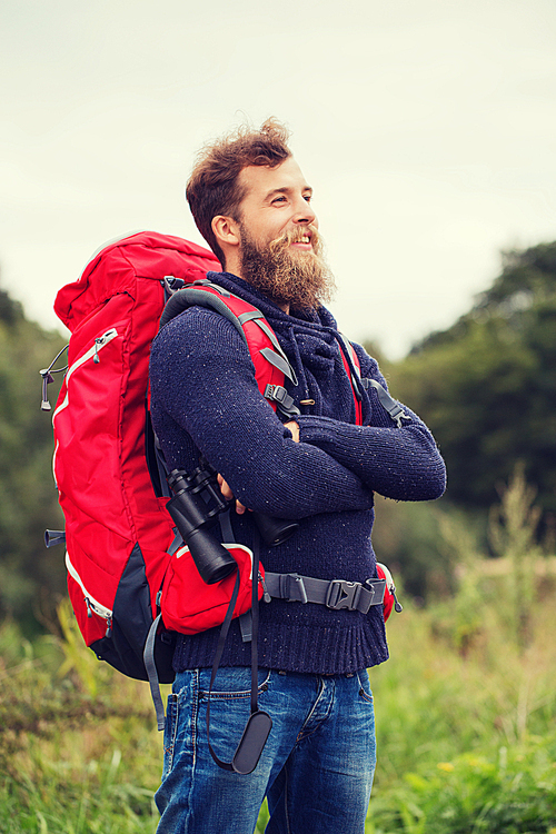 adventure, travel, tourism, hike and people concept - smiling man with red backpack and binocular outdoors