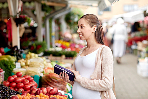 sale, shopping, pregnancy and people concept - happy pregnant woman with wallet and money buying food at street market