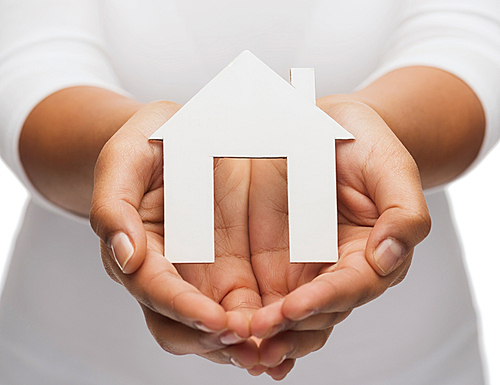 real estate concept - closeup of woman hands holding paper house