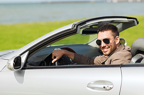 auto business, transport, leisure and people concept - happy man driving cabriolet car outdoors