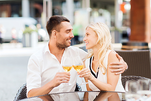 love, dating, people and holidays concept - smiling couple clinking glasses and looking to each other at restaurant lounge or terrace