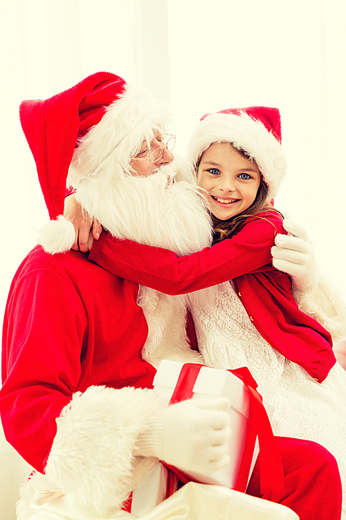 holidays, christmas, happiness and people concept - smiling girl with gift box embracing santa claus at home