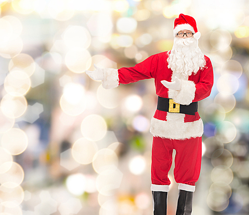 christmas, holidays, gesture and people concept - man in costume of santa claus over lights background