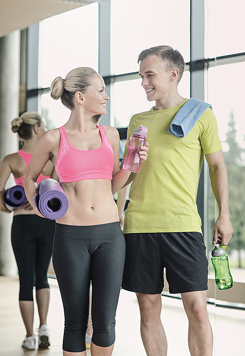 sport, fitness, lifestyle and people concept - smiling couple with water bottles in gym