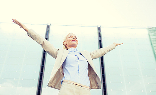 business, people and education concept - young smiling businesswoman over office building