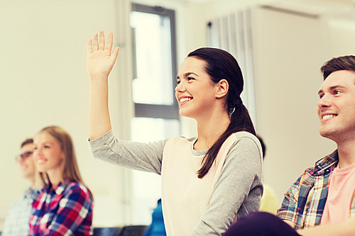 education, high school, teamwork and people concept - group of smiling students raising hand in lecture hall