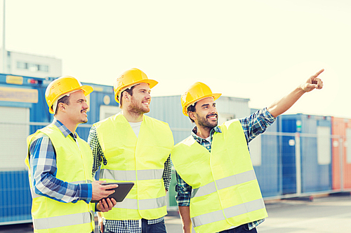 business, building, teamwork, technology and people concept - group of smiling builders in hardhats with tablet pc computer outdoors