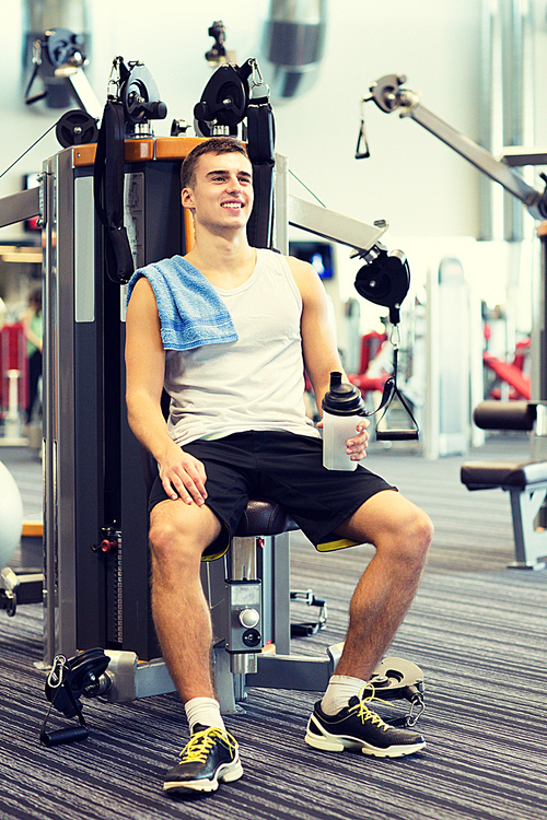 sport, fitness, equipment, lifestyle and people concept - smiling man exercising on gym machine