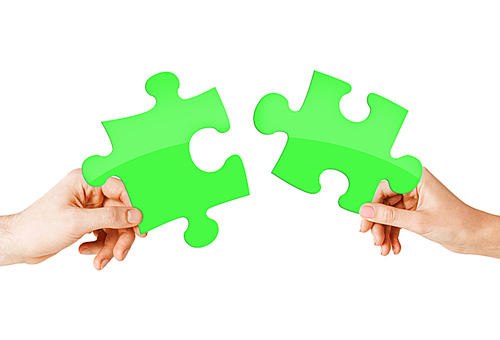 nature, ecology, energy saving and people concept - close up of couple hands trying to connect green puzzle pieces