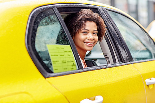 business trip, transportation and people concept - young smiling african american woman driving in taxi at city street