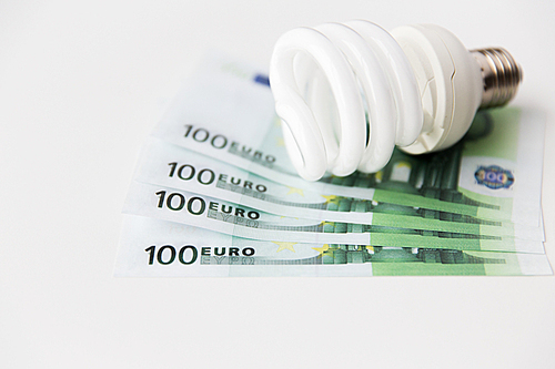 business, finance, energy saving and utilities concept - close up of euro paper money and light bulb on table