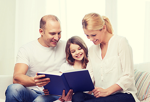 family, child and home concept - smiling parents and little girl with book at home