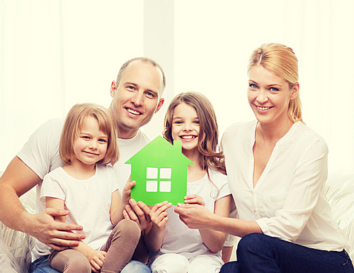 real estate, family, children and home concept - smiling parents and two little girls holding green house