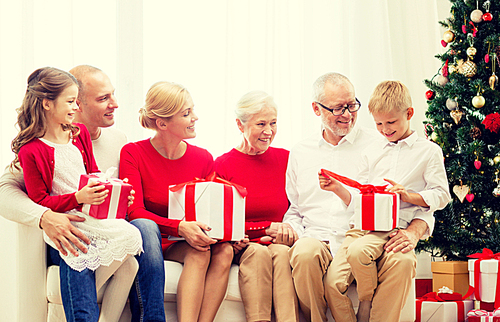 family, holidays, generation, christmas and people concept - smiling family with gift boxes sitting on couch at home