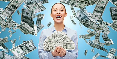 business, money, finance, people and banking concept - happy laughing businesswoman with heap of dollar cash money over blue background