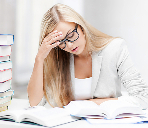 student with pile of books and notes studying indoors