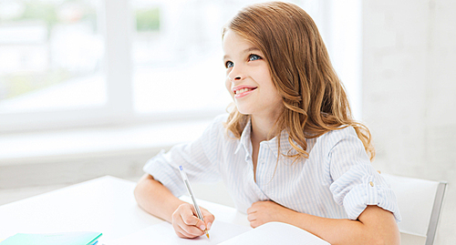 education and school concept - little student girl writing in notebook at school