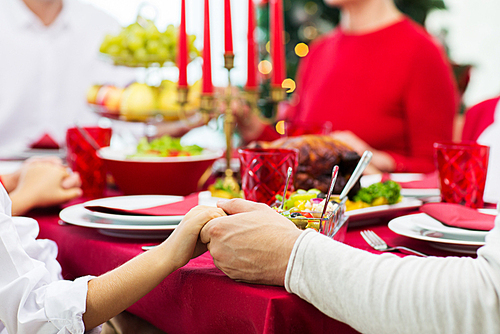 family, holiday, tradition, generation and people concept - close up of family having christmas dinner and holding hands at home