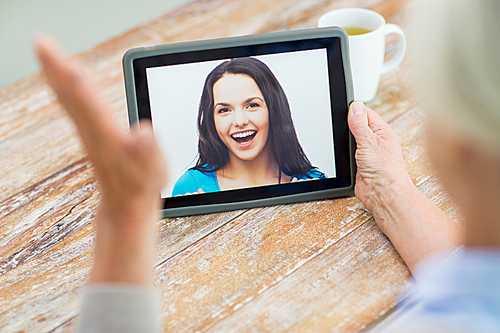 technology, age, memories and people concept - happy senior woman with tablet pc computer viewing photo or having video chat with granddaughter at home