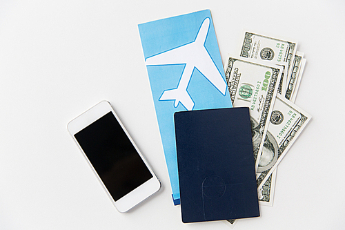 tourism, travel and objects concept - air ticket, money, smartphone and passport on table