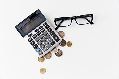 busines, finance, money and bookkeeping concept - calculator, eyeglasses and euro coins on office table