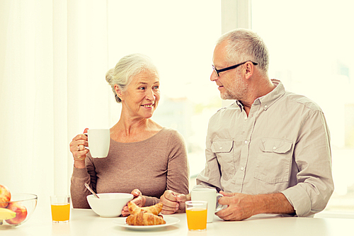 family, technology, food, drinks and people concept - happy senior couple having breakfast at home