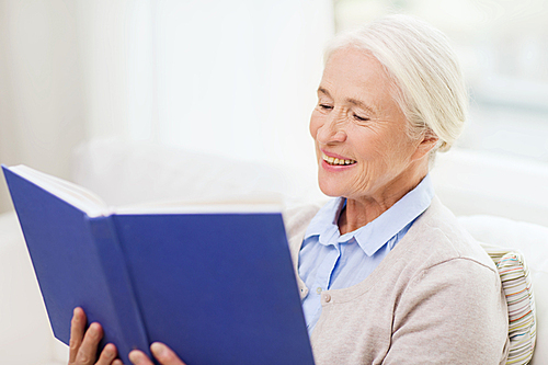 age, leisure and people concept - happy smiling senior woman reading book at home